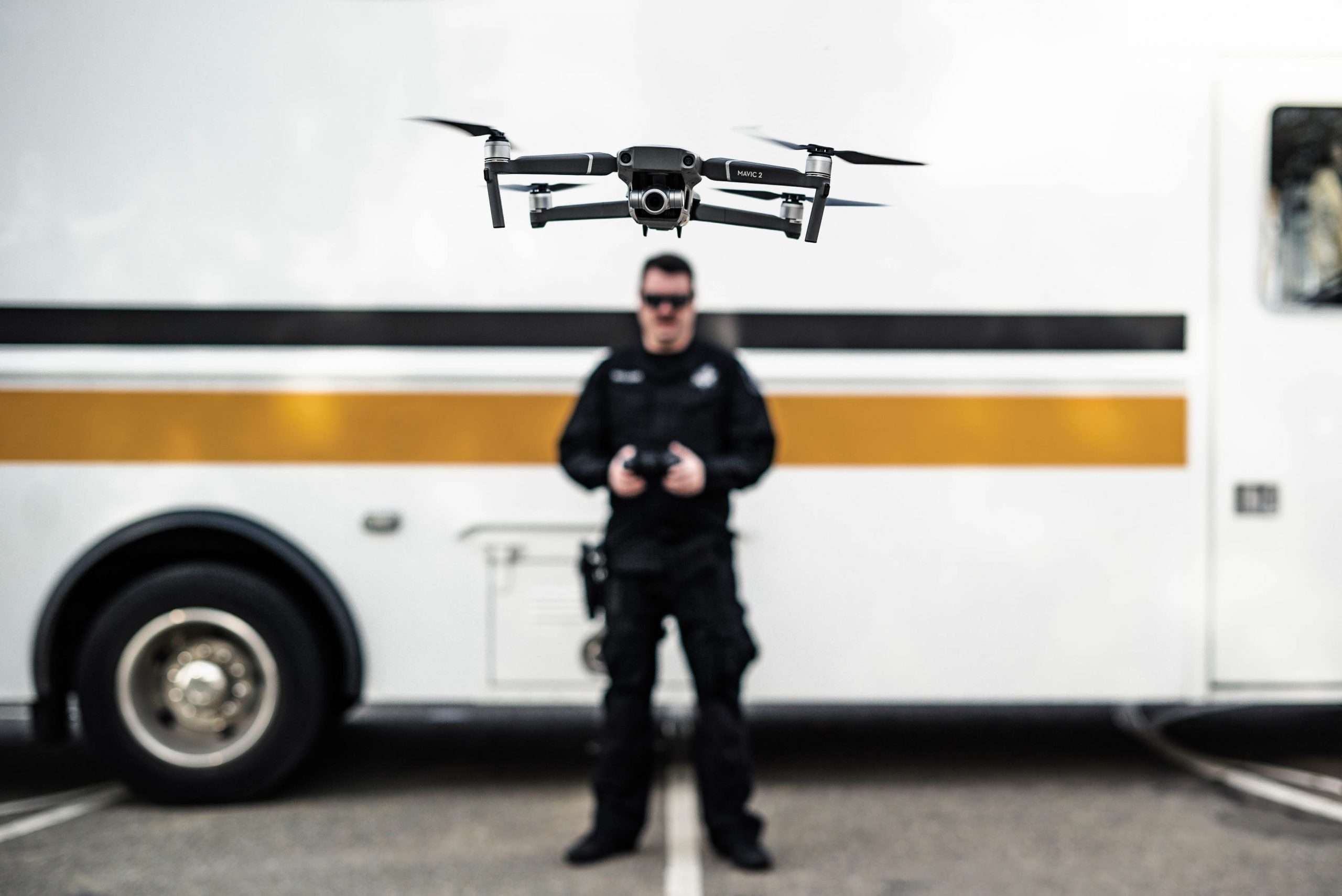 A police drone operator flies a drone in front of the camera