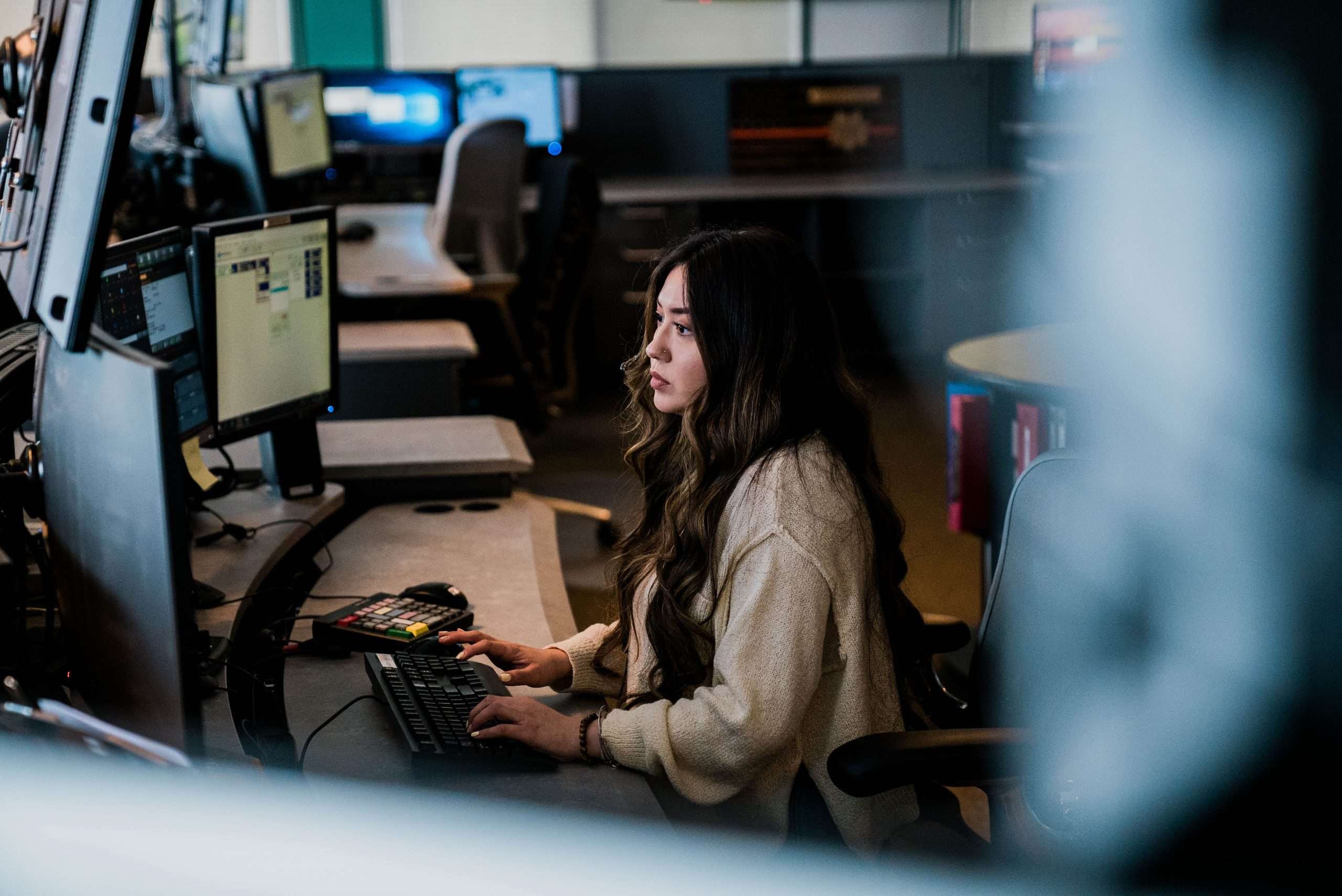 A police dispatcher types on a computer while speaking to a 911 caller